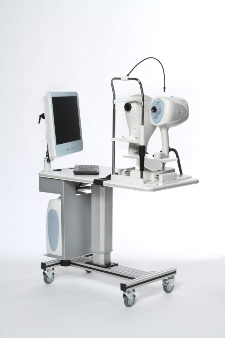 A computer monitor and eye exam equipment on a cart.