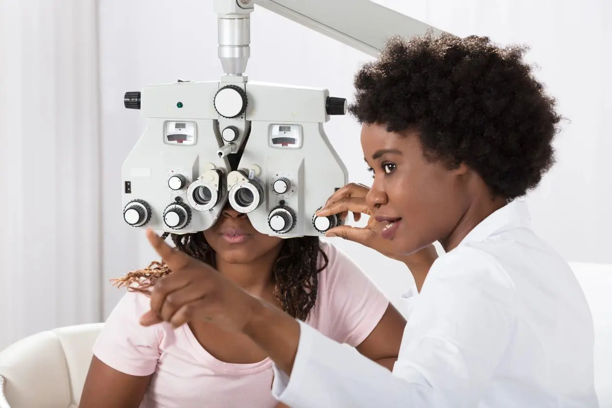 A woman is looking through the lens of an eye exam.